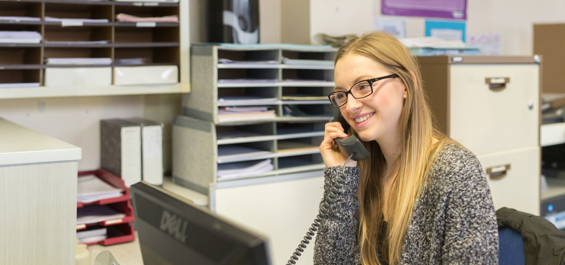 Work Placements for Parents and Carers Alt text A student smiling while on the phone in an office